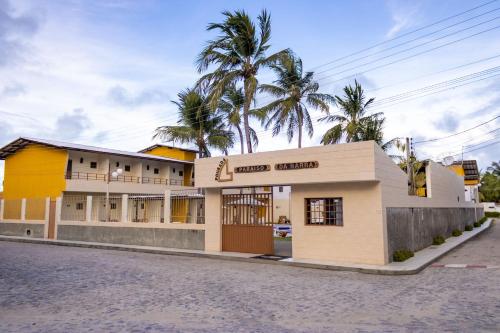 a building on a street with palm trees in the background at Pousada Paraiso da Barra in Barra de Santo Antônio
