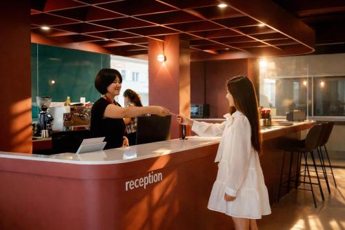 a woman is helping a girl at a bar at Quicky Stay Airport in Min Buri
