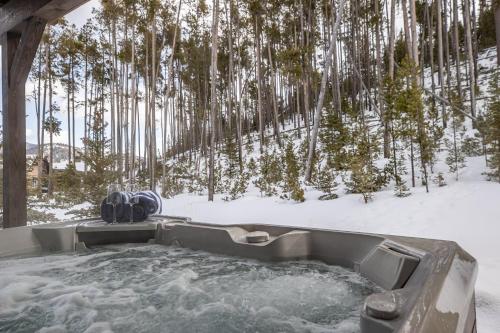 a jacuzzi tub in the snow with trees at Spanish Peaks - Highlands Cabin 36 in Big Sky