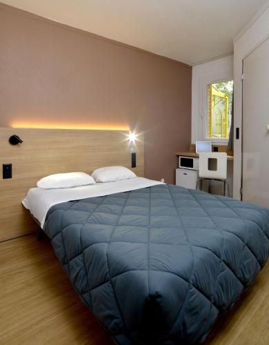 a bedroom with a large bed with a blue blanket at Premiere Classe Nancy Est Essey in Essey-lès-Nancy