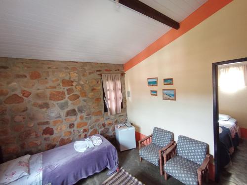 a bedroom with two beds and a stone wall at Pousada Café do Brejo in Triunfo