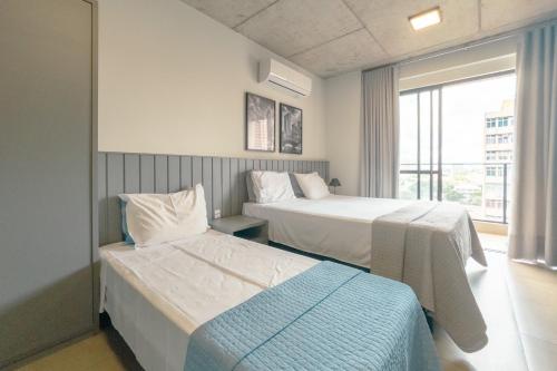 a hotel room with two beds and a window at Moderno e Central - CA905 in Maringá