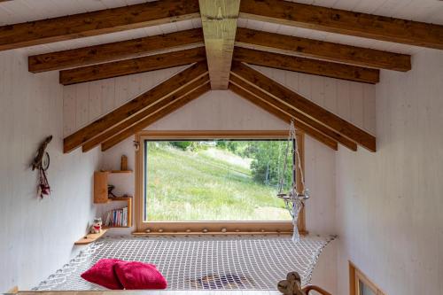 a room with a hammock in a room with a window at Tiny de l'Aigle in Villeret