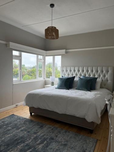 a bedroom with a large bed with blue pillows at Bird Rock Sunrise in Gqeberha