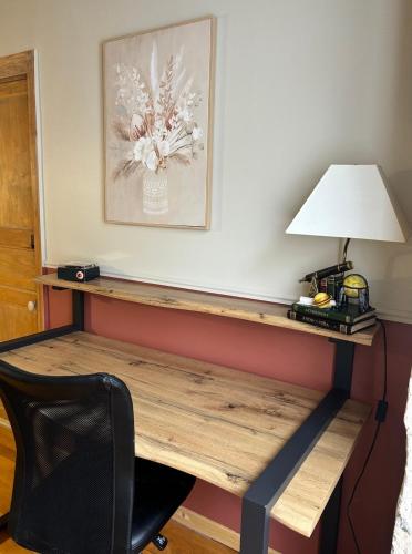 a desk in a room with a lamp and a chair at La Pierre du Bonheur in Saint-Denis-dʼAnjou