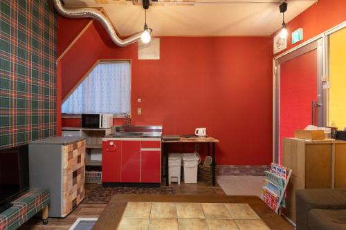 a kitchen with red walls and red cabinets at Private house YOURSとなり in Osaka