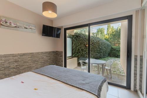 una camera da letto con un letto e un patio con un tavolo di Les Sarments a Le Lavandou