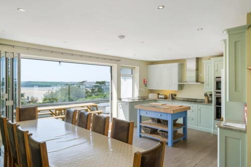 a kitchen with a table and chairs and a large window at Beautiful Home with Pool Overlooking Camel Estuary in Roche