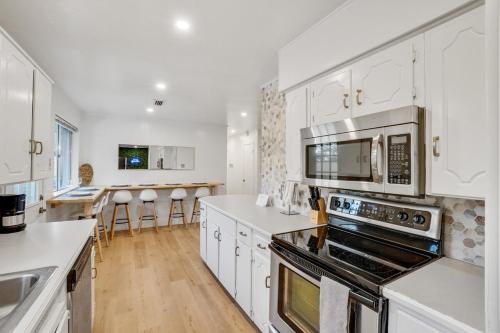 a kitchen with white cabinets and a stove top oven at Holiday 4BR 2BA Home with Pool, Hot Tub, Fire Pit in Irving