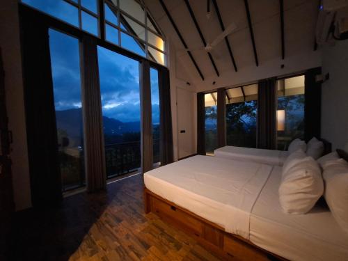 a bedroom with a white bed with large windows at Highgarden Hideaway Villa - Gampola in Gampola