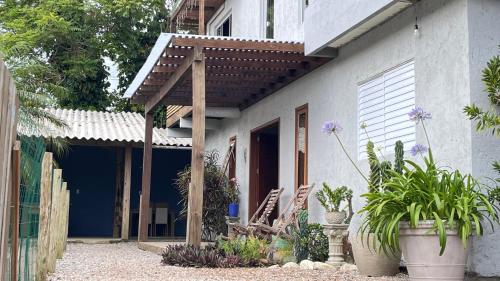 a white house with a wooden pergola on it at Casa das Palmeiras in Imbituba