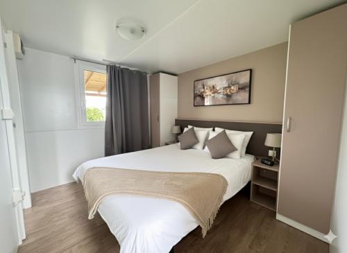 a bedroom with a large white bed and a window at Mobile Homes Relax Park Umag in Umag