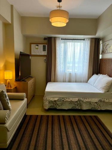 ein Schlafzimmer mit einem Bett und einem Fenster mit einer Couch in der Unterkunft KBrothers - Chic Studio in the Heart of it All! in Cagayan de Oro