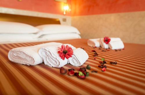 zwei Handtücher und ein paar Blumen auf dem Bett in der Unterkunft Terrazza San Pietro in Rom