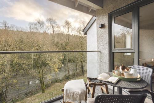 a balcony with a table and chairs and a large window at Exceptional 3 Bedroom River View Apartment - Pass the Keys in Ulverston