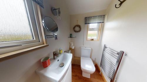 a bathroom with a toilet and a sink and a window at E08 Boness E8, Riviere Towans in Hayle
