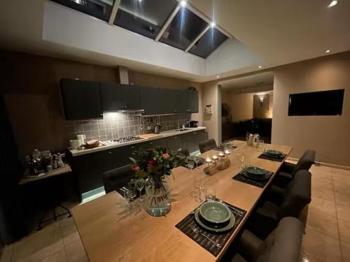 a dining room with a long table and a kitchen at Gasthuys Rooy in Stramproy