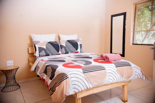 a bedroom with a bed with a colorful comforter at Falcon Lodge ET in Bela-Bela