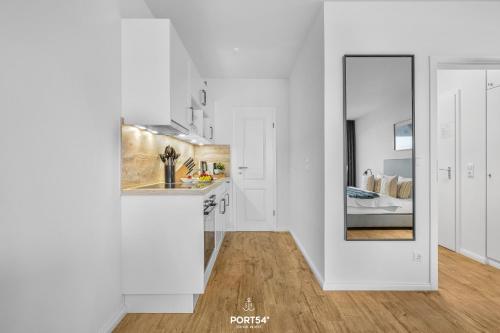 a white kitchen with a mirror on the wall at Ferienwohnung Seeblick 203 Büsum in Büsum