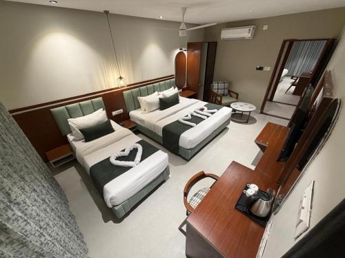 a hotel room with two beds and a table at MR Suites Dharwad in Dhārwād