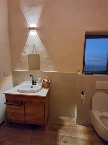 a bathroom with a sink and a toilet and a light at שיר ערש in Giv'at Yo'av