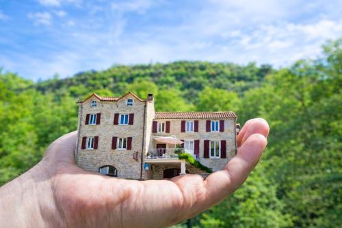 a person holding a house in their hand at LES GARGOUILLES - Piscine à Débordement Avec Vue Exceptionnelle - Gorges du Tarn - Millau in Boyne