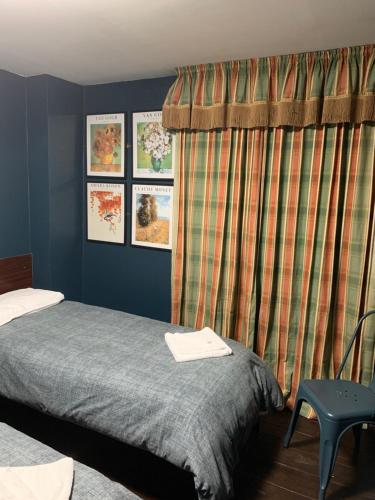 a bedroom with a bed and a curtain and a chair at Four Stars Hotel in London