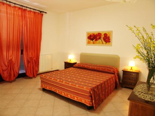 a bedroom with a bed with red curtains and two lamps at Le Ginestre Arte Vacanze in Chianciano Terme