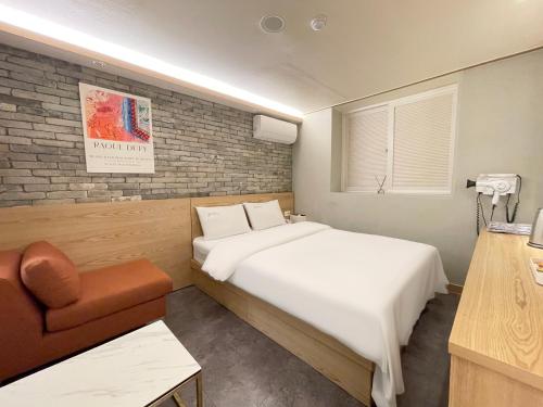 a bedroom with a white bed and a chair at Gallery Motel in Seongnam