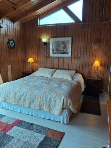 a bedroom with a large bed in a wooden wall at Entre Espinos in Lo Chaparro