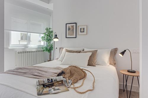 a white bedroom with a white bed and a table at Main Street Deluxe in A Coruña