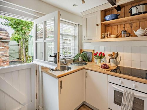 a kitchen with white cabinets and a sink and a window at 1 Bed in Tenterden oc-66342 in Tenterden