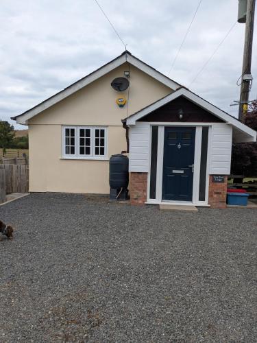 a small white house with a blue door at Tanyfford Lodge, Abermule, Mid Wales, SY15 6NT in Abermule