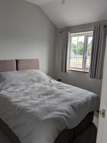a white bed in a bedroom with a window at Tanyfford Lodge, Abermule, Mid Wales, SY15 6NT in Abermule