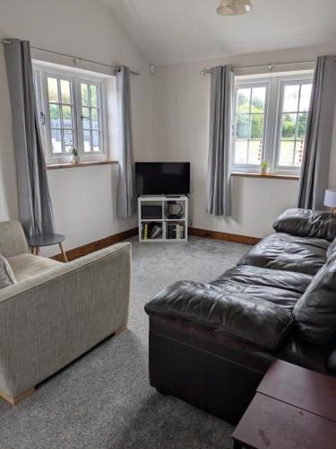 a living room with a couch and a tv at Tanyfford Lodge, Abermule, Mid Wales, SY15 6NT in Abermule