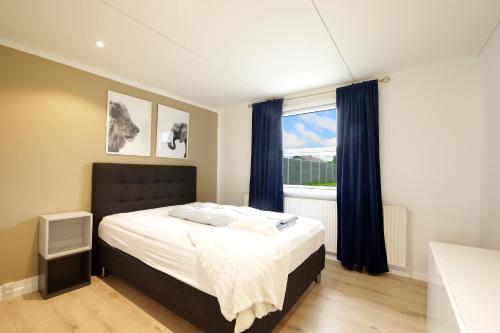 a bedroom with a bed with blue curtains and a window at Granlunden id089 in Esbjerg