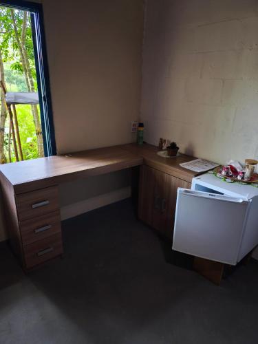 a kitchen with a desk and a white refrigerator at Chalé no Plantar em Casa in São Roque