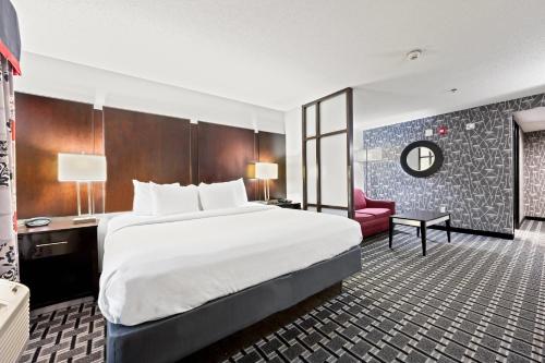 a hotel room with a large bed and a red chair at Comfort Suites Williamsburg Historic Area in Williamsburg