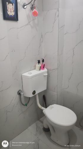 a bathroom with a white toilet and a sink at Kozy Cottage udaipur in Udaipur