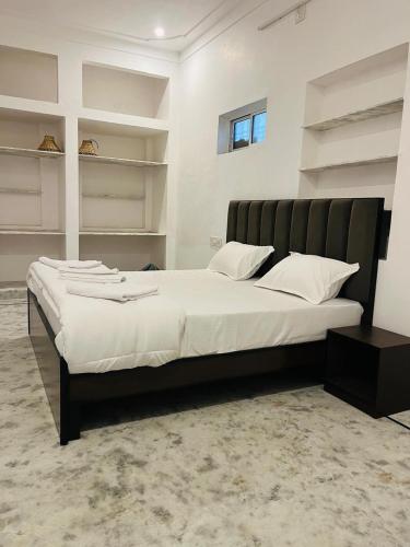 a bedroom with a large white bed with shelves at Kozy Cottage udaipur in Udaipur