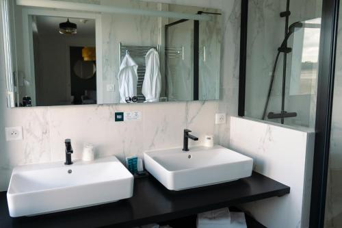 a bathroom with two white sinks and a mirror at Logis Hôtel de la Pointe du Cap Coz in Fouesnant
