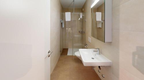a white bathroom with a sink and a shower at Relax and Recharge By The Lake! Modern Morges Apartments, AP26 in Morges