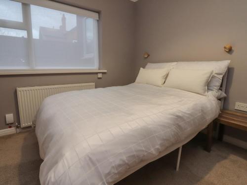a white bed in a room with a window at Seaside Serenity in Lytham St Annes