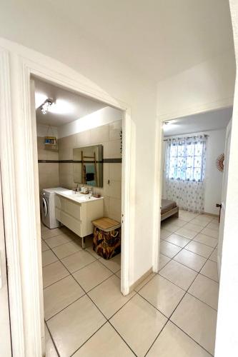a white bathroom with a sink and a mirror at Blue Marine Apartment in Baie Nettle