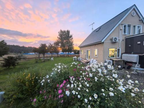 a house with a field of flowers in front of it at Hillview cottage Sanfurano in Kami-furano