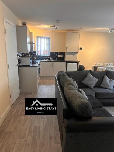a living room with a couch and a kitchen at Easy Living Stays Burton on Trent in Burton upon Trent