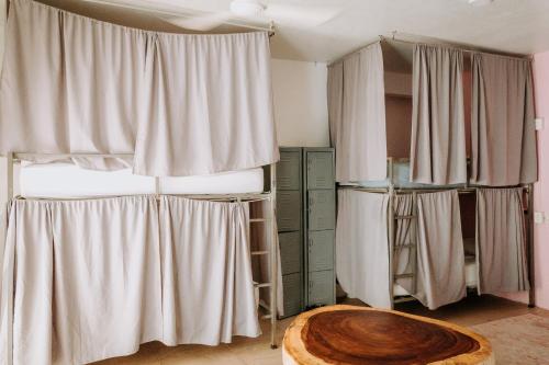 a room with a bed with curtains and a table at SurfNest Hostel in Brisas de Zicatela