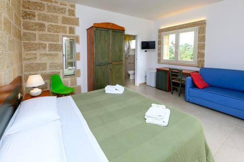 a bedroom with a bed and a blue couch at Agriturismo Tenuta Calitre in Melendugno