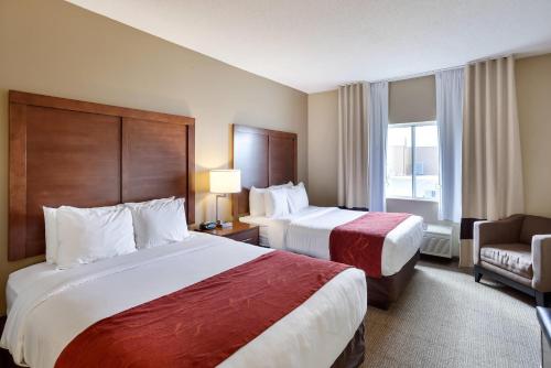 a hotel room with two beds and a chair at Comfort Suites Lincoln North in Lincoln