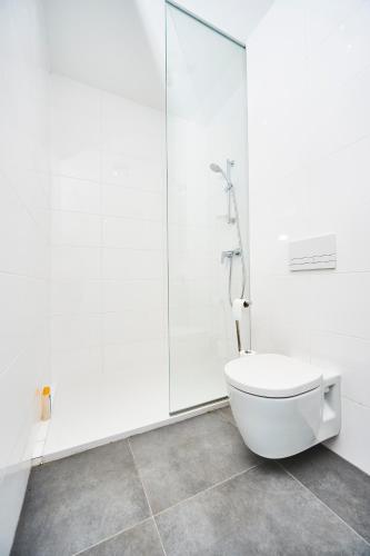 a white bathroom with a toilet and a shower at Cube Apartamenty in Lublin